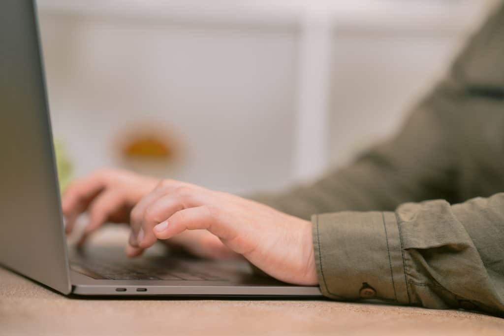 Programmer writing code on laptop keyboard working from home